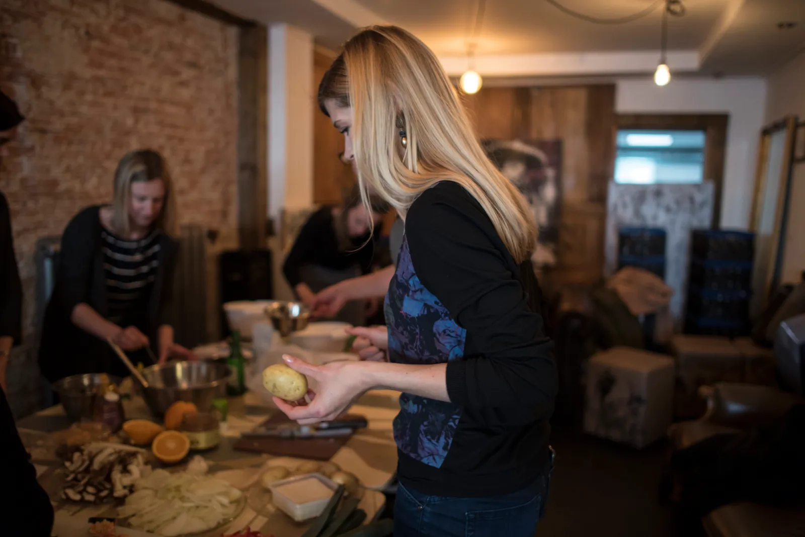 Deltagare skalar potatis vid ett gemensamt förberedelsebord under en matlagningskurs i grupp
