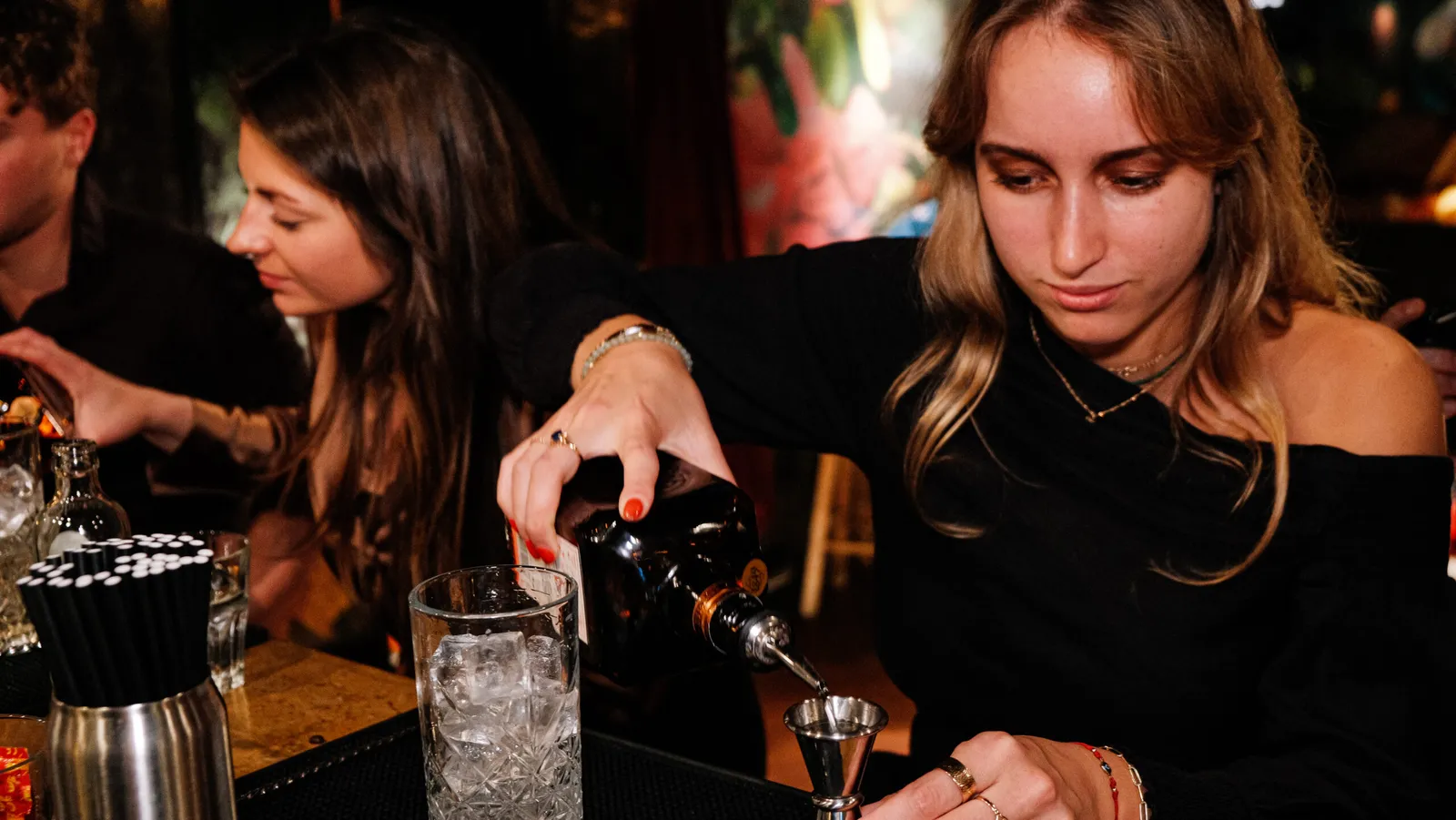 Guest measuring a spirit with a jigger into a mixing glass