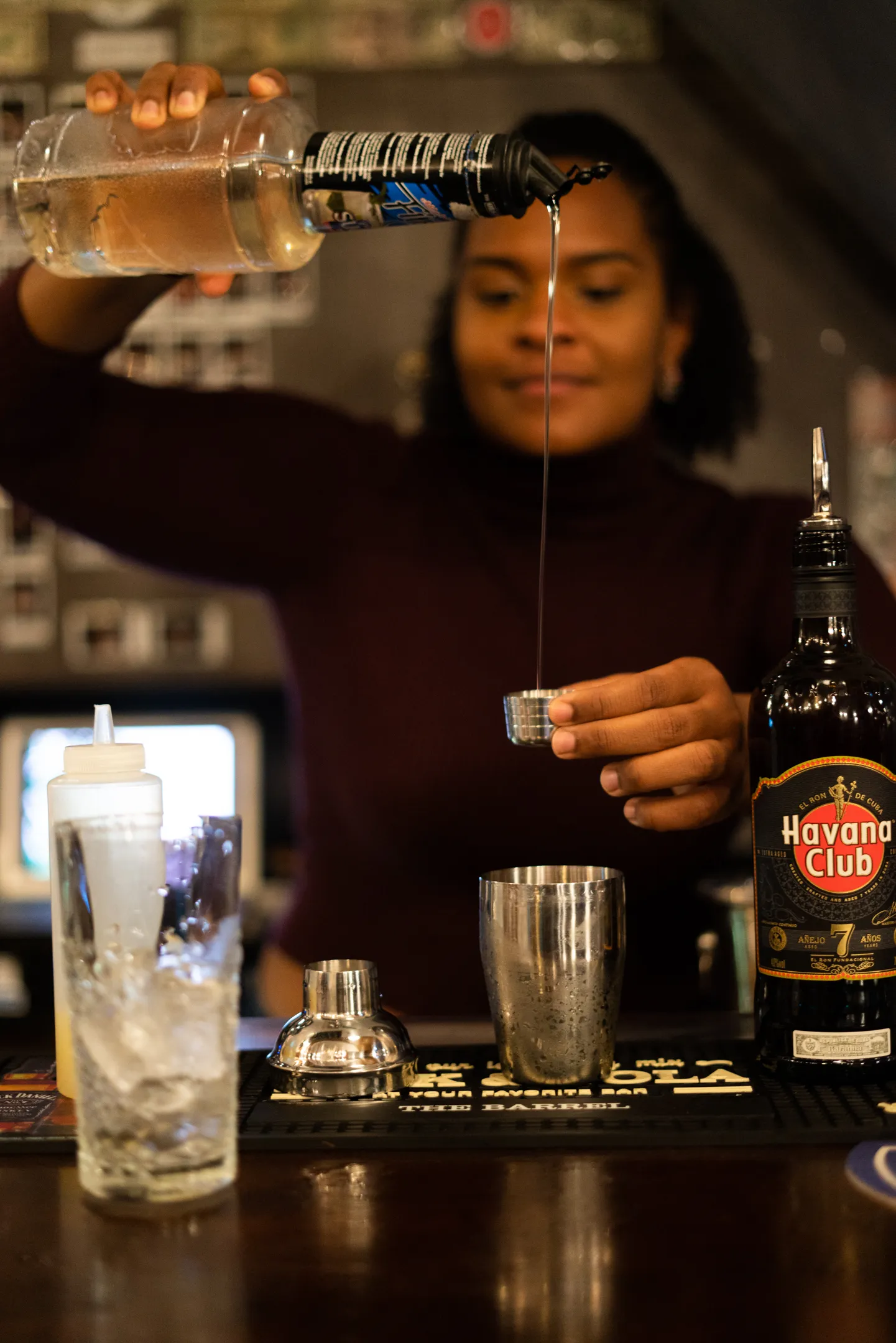Bartender pouring a spirit from height into a jigger behind the bar