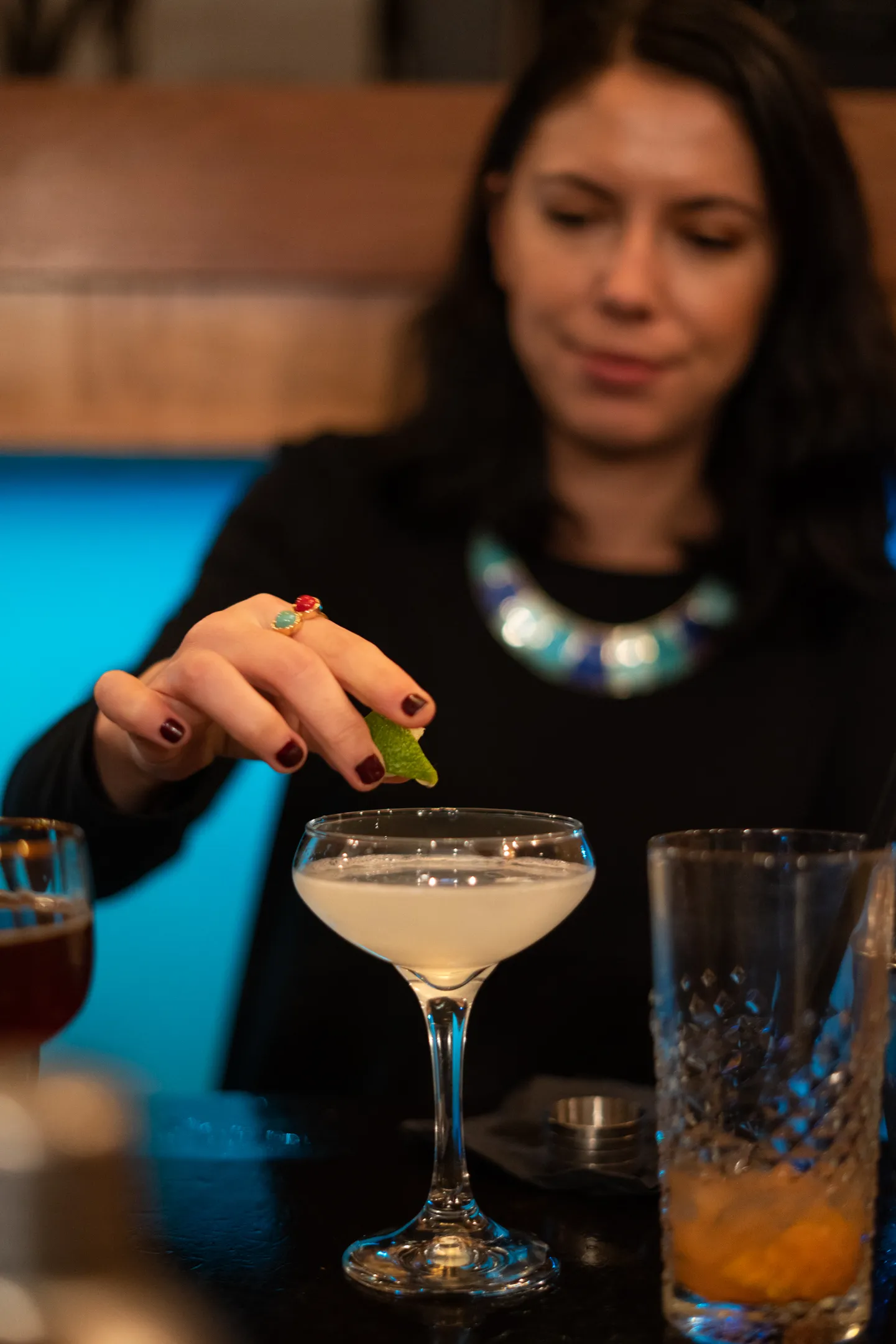 Guest adding a garnish to a cocktail in a coupe glass at the bar