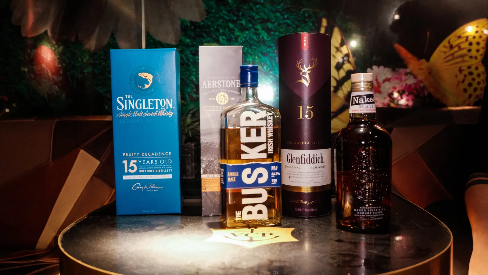 Flasker og æsker med single malt whisky stillet op på et rundt smagebord