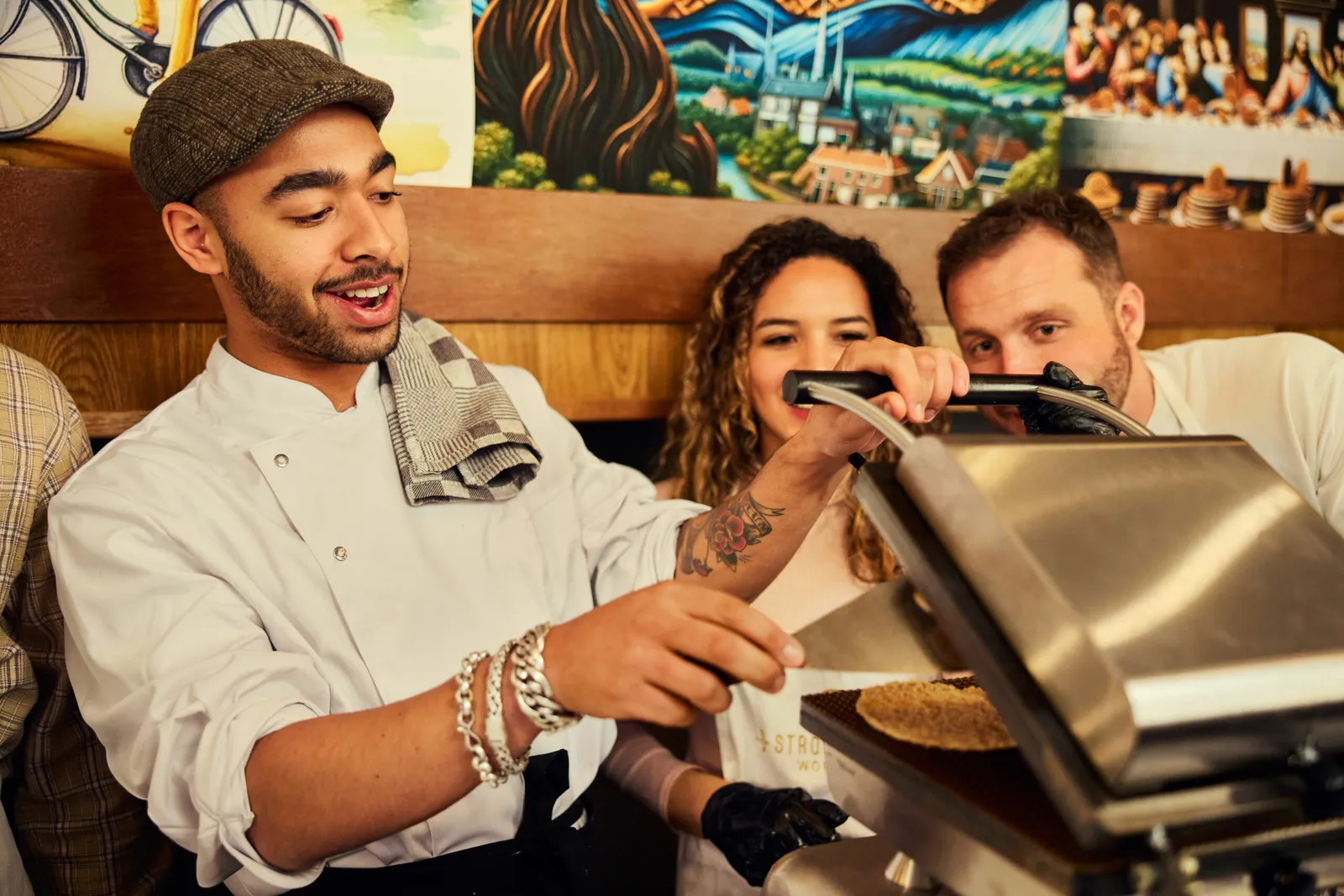 Guest opening a hot waffle iron while two others watch and laugh
