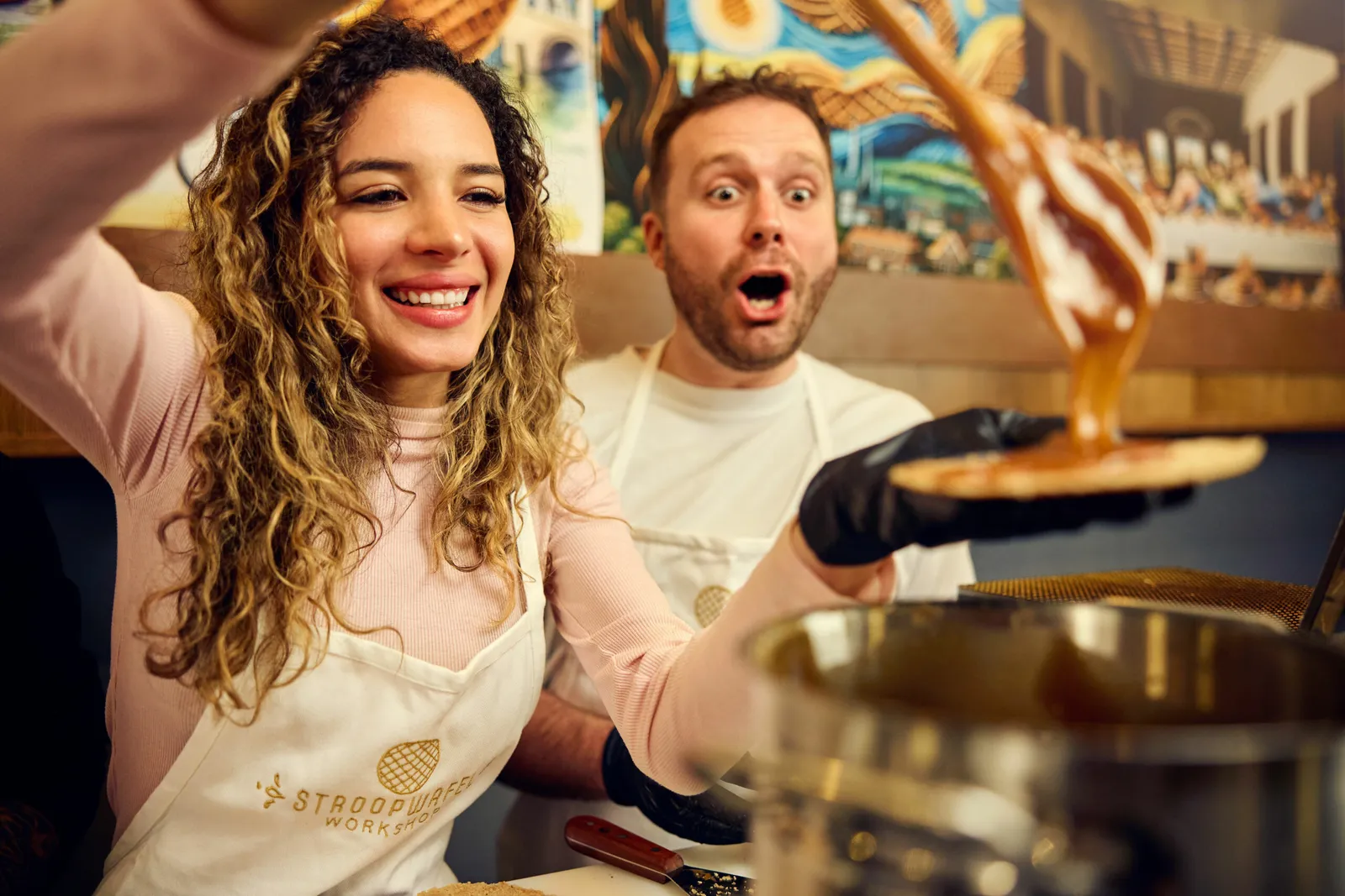 Guests reacting as warm syrup drips from a spoon onto a stroopwafel