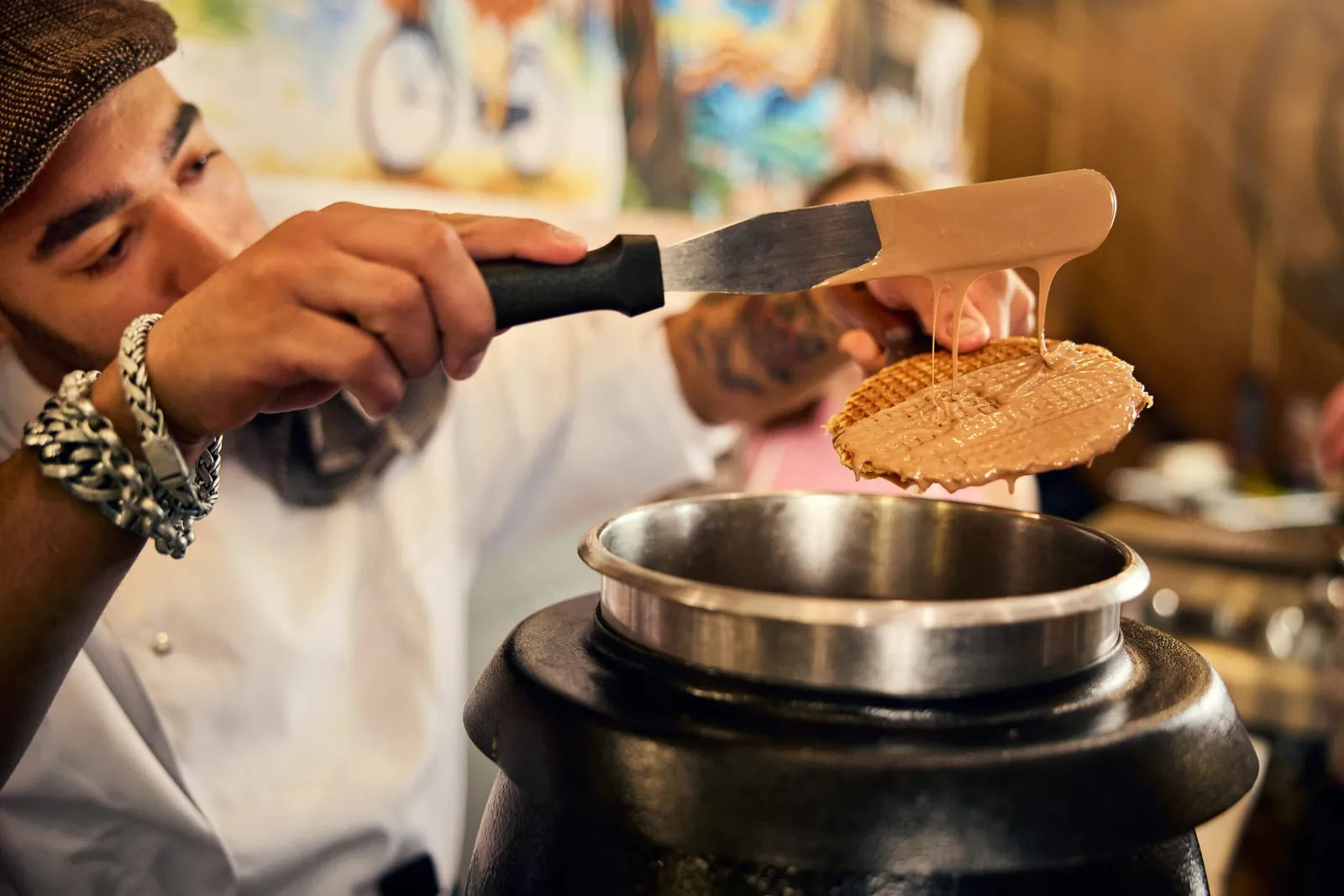 Spreading warm caramel syrup on a freshly baked stroopwafel with a spatula